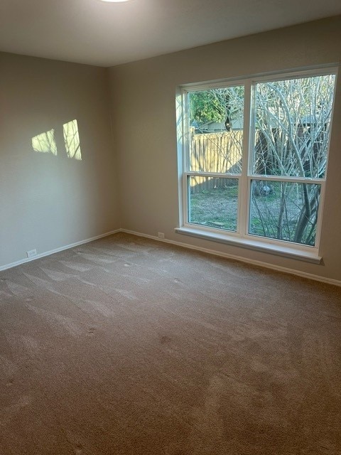 spare room featuring dark carpet and baseboards