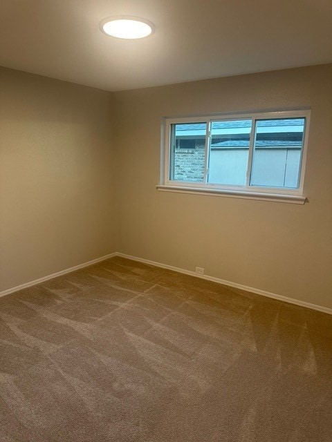 spare room featuring visible vents, dark carpet, and baseboards