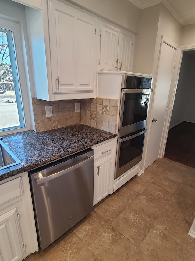 kitchen with white cabinetry, appliances with stainless steel finishes, decorative backsplash, and dark stone counters