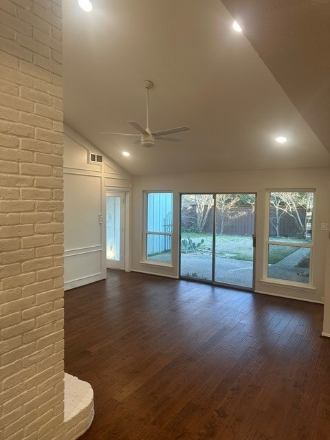 unfurnished living room with dark wood-style floors, high vaulted ceiling, a brick fireplace, and a ceiling fan