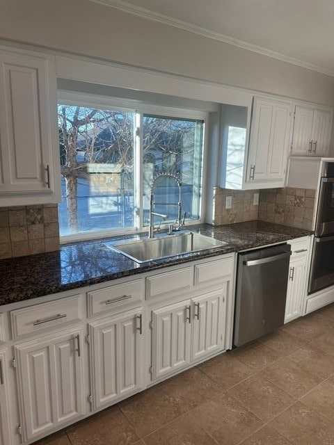 kitchen with appliances with stainless steel finishes, ornamental molding, a sink, white cabinetry, and backsplash