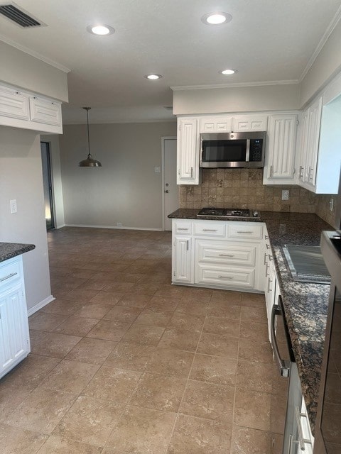 kitchen with black gas cooktop, stainless steel microwave, hanging light fixtures, visible vents, and white cabinetry