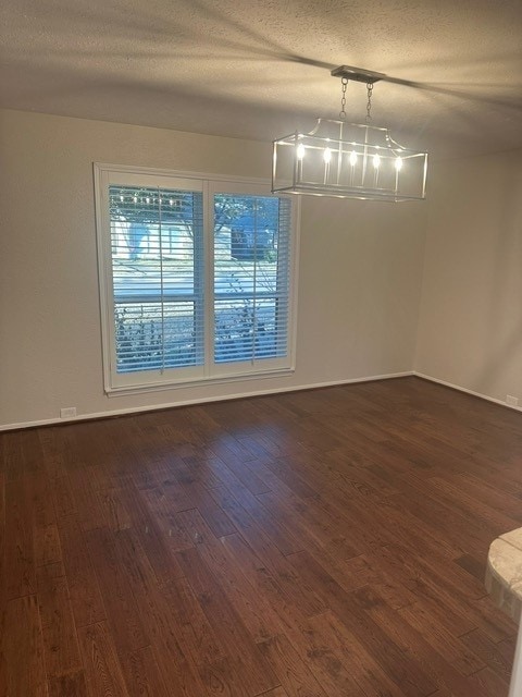 unfurnished room with dark wood-type flooring and a textured ceiling