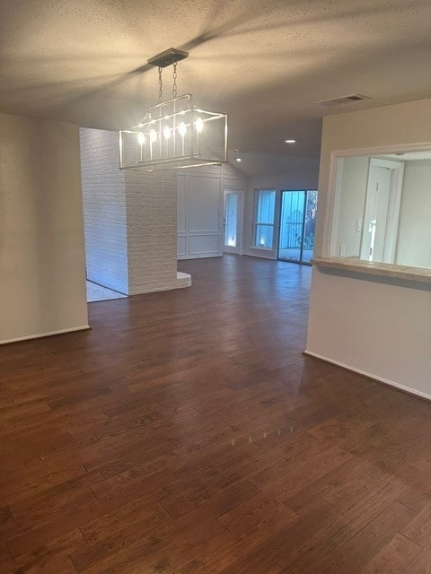 unfurnished room with a textured ceiling, dark wood finished floors, and visible vents