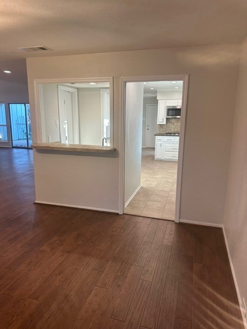 unfurnished room with baseboards, a textured ceiling, visible vents, and wood finished floors