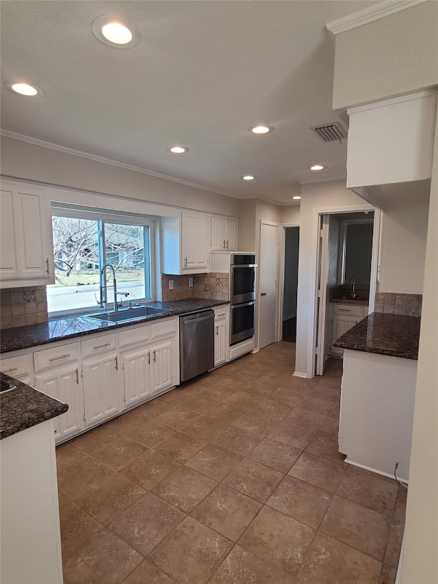 kitchen with appliances with stainless steel finishes, sink, white cabinets, and decorative backsplash