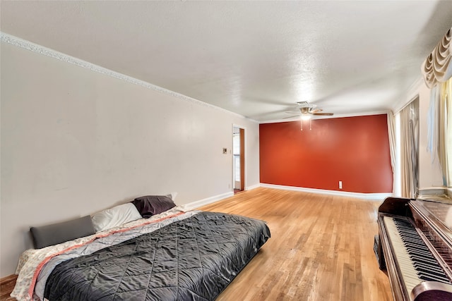 bedroom with hardwood / wood-style flooring, a textured ceiling, ornamental molding, and ceiling fan