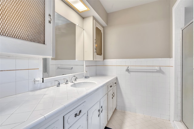 bathroom with a shower, vanity, tile patterned floors, and tile walls