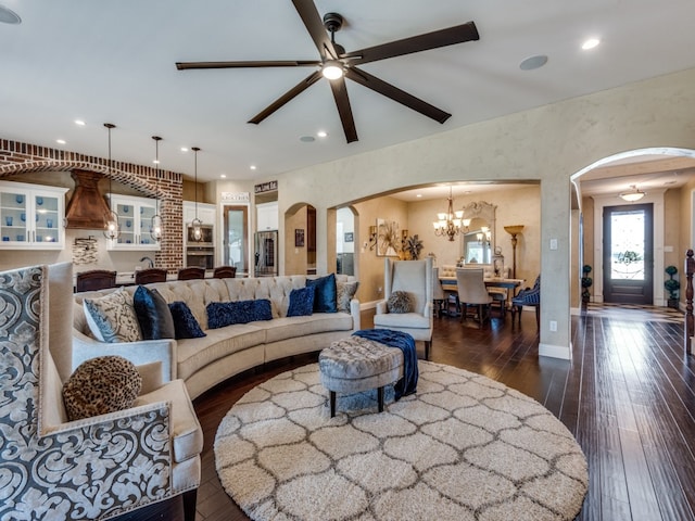 living room with ceiling fan with notable chandelier and dark hardwood / wood-style floors