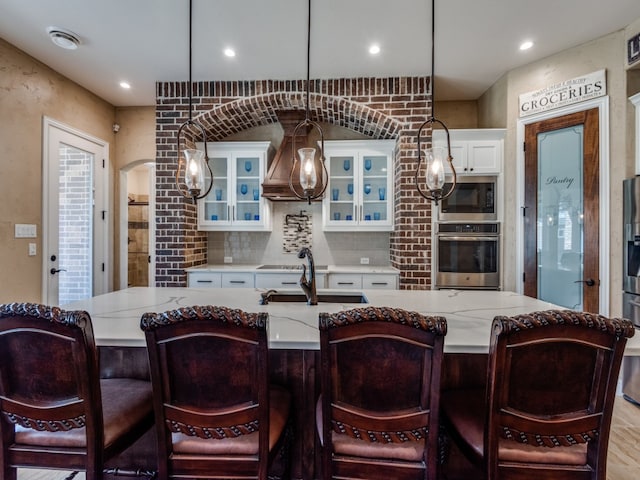 kitchen featuring stainless steel appliances, white cabinetry, decorative light fixtures, and light hardwood / wood-style flooring