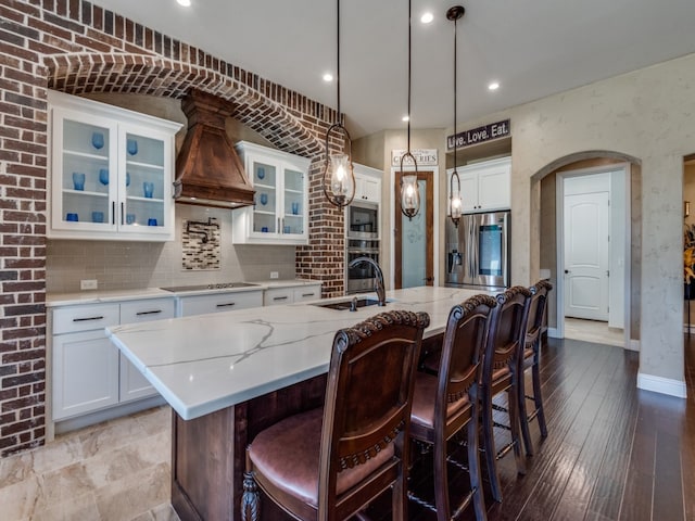 kitchen featuring a kitchen island with sink, white cabinetry, sink, and premium range hood