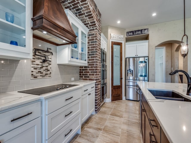 kitchen with sink, white cabinetry, custom range hood, and stainless steel appliances