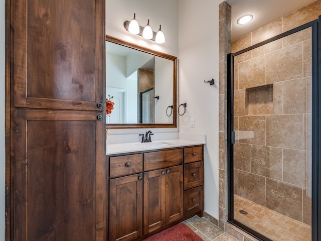 bathroom with a shower with door, vanity, and tile patterned flooring