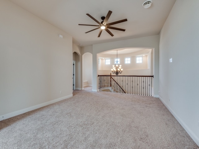 spare room with ceiling fan with notable chandelier and carpet flooring