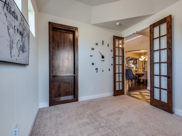 spare room featuring light carpet, an inviting chandelier, and french doors