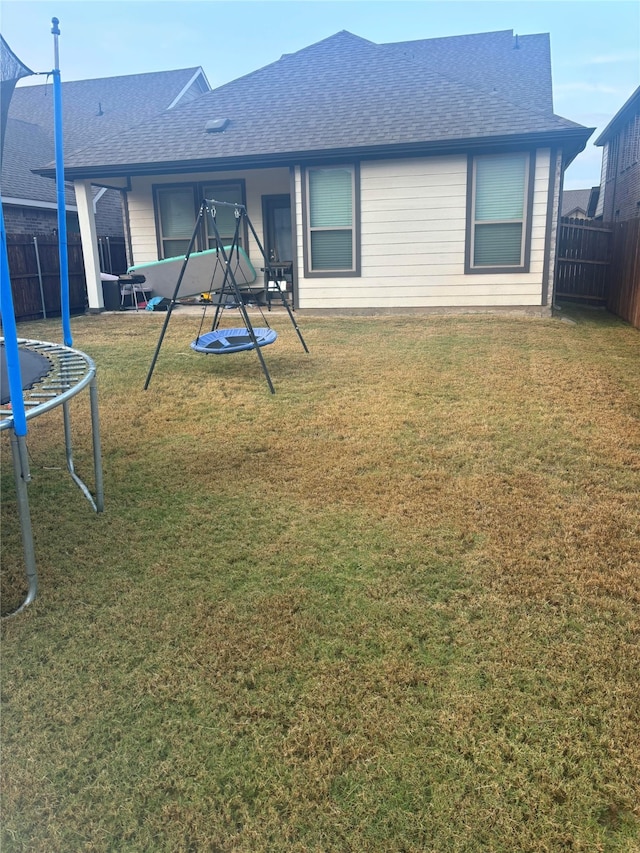 rear view of house featuring a lawn and a trampoline