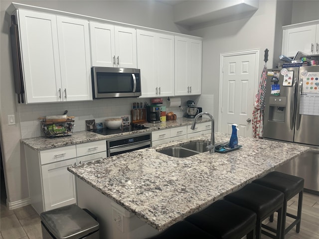 kitchen featuring a kitchen breakfast bar, sink, light wood-type flooring, and appliances with stainless steel finishes