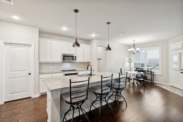 kitchen featuring dark wood-type flooring, appliances with stainless steel finishes, a chandelier, white cabinets, and pendant lighting