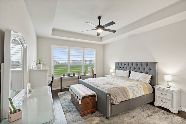 bedroom featuring a tray ceiling, wood-type flooring, and ceiling fan