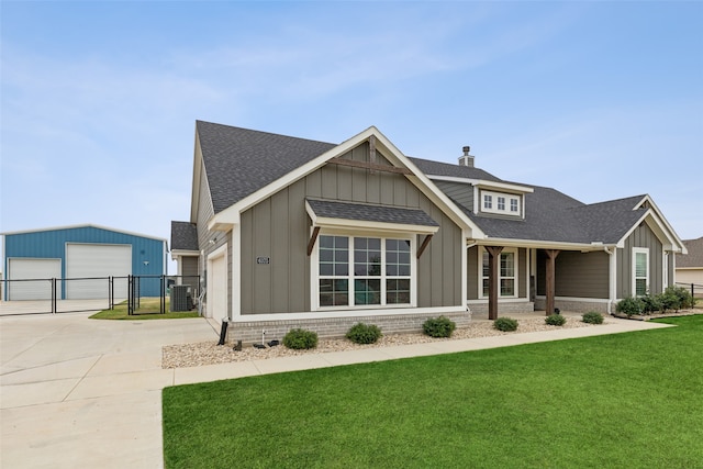 view of front of property with a garage, an outdoor structure, central air condition unit, and a front lawn