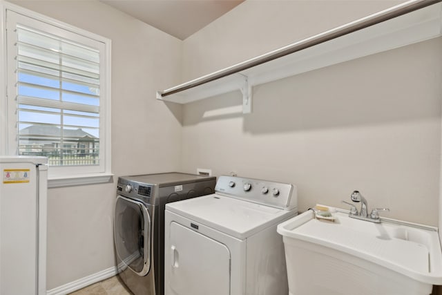 clothes washing area with washer and clothes dryer, sink, and light tile patterned floors