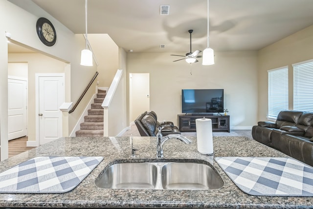 kitchen with dark stone counters, hardwood / wood-style flooring, sink, ceiling fan, and pendant lighting