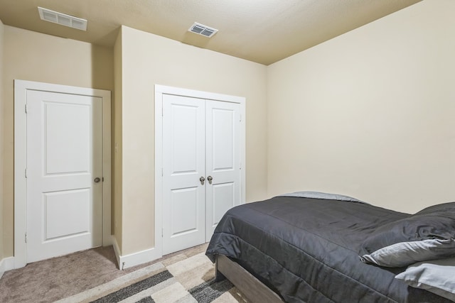 bedroom with a textured ceiling, light carpet, and a closet