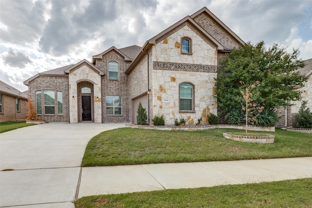 french country home featuring a garage and a front lawn