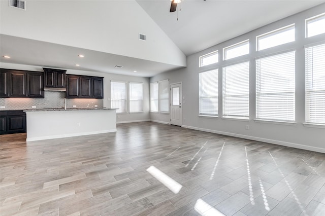 unfurnished living room with ceiling fan and high vaulted ceiling