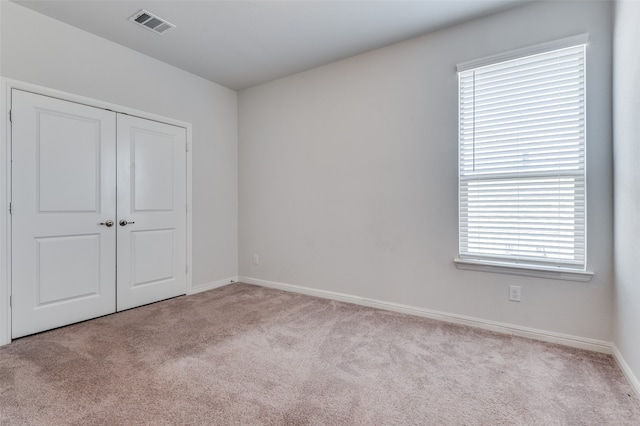 unfurnished bedroom featuring light carpet and a closet