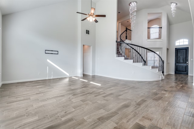 unfurnished living room featuring ceiling fan and a towering ceiling