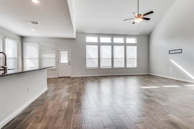 unfurnished living room featuring hardwood / wood-style flooring, ceiling fan, sink, and a wealth of natural light