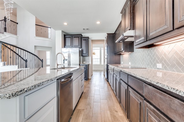 kitchen featuring a notable chandelier, ventilation hood, sink, appliances with stainless steel finishes, and dark brown cabinets