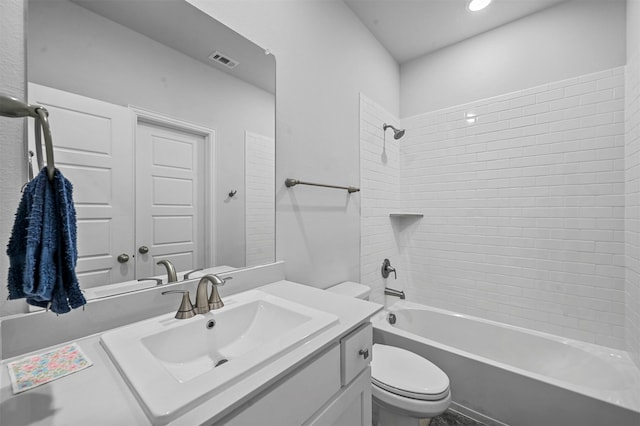 full bathroom featuring vanity, tiled shower / bath combo, and toilet