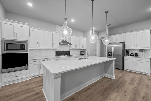 kitchen featuring stainless steel appliances, hanging light fixtures, white cabinetry, and sink