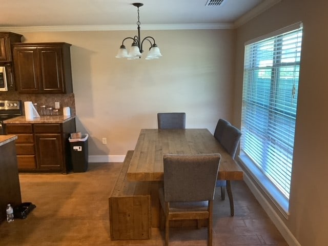 dining area with ornamental molding and an inviting chandelier