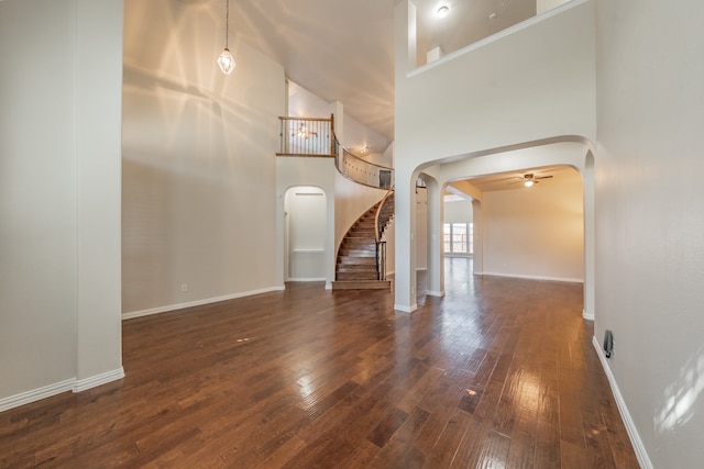 unfurnished living room featuring high vaulted ceiling, dark hardwood / wood-style flooring, and ceiling fan