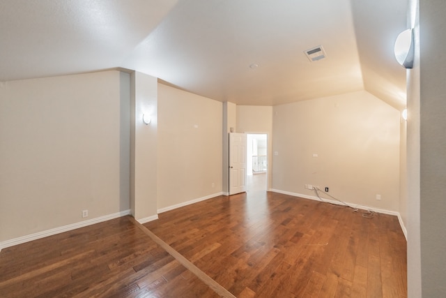 empty room with dark wood-type flooring and lofted ceiling