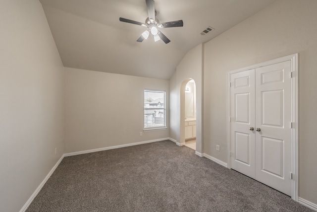 unfurnished bedroom with lofted ceiling, carpet floors, ensuite bathroom, ceiling fan, and a closet