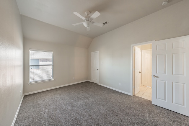 carpeted spare room featuring vaulted ceiling and ceiling fan