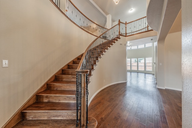 stairs with hardwood / wood-style floors and a towering ceiling