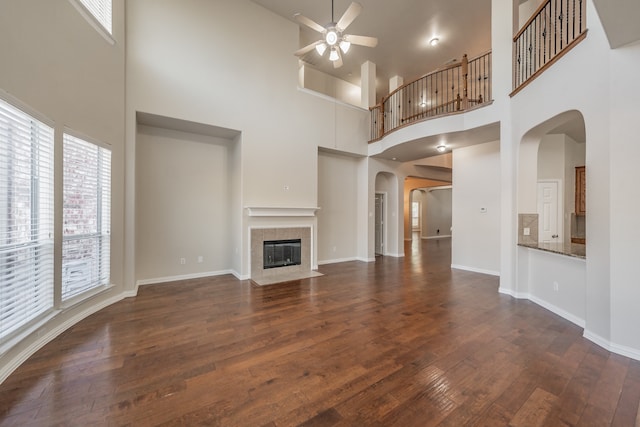 unfurnished living room featuring dark wood-type flooring, a high ceiling, and a tile fireplace