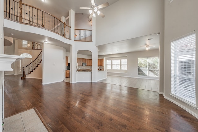 unfurnished living room featuring a high ceiling, hardwood / wood-style floors, and ceiling fan