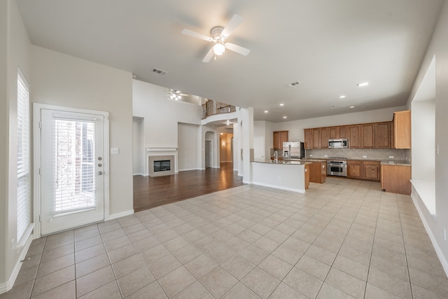 kitchen featuring kitchen peninsula, appliances with stainless steel finishes, backsplash, and light tile patterned floors