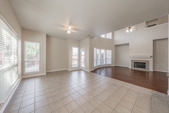 unfurnished living room featuring light tile patterned floors, ceiling fan, and a fireplace