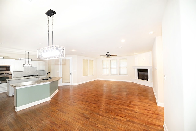 kitchen with appliances with stainless steel finishes, tasteful backsplash, ceiling fan, decorative light fixtures, and wood-type flooring