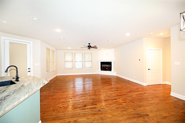 unfurnished living room with ceiling fan, wood-type flooring, and sink