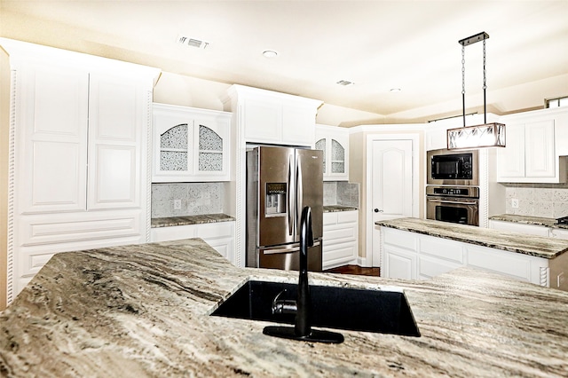 kitchen with tasteful backsplash, stainless steel appliances, decorative light fixtures, light stone countertops, and white cabinets