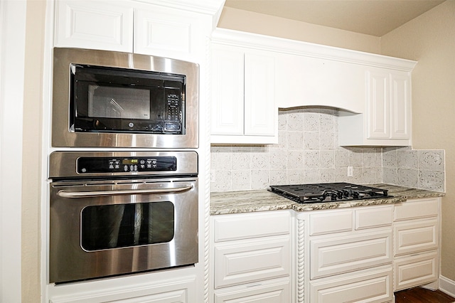 kitchen featuring light stone counters, white cabinets, black appliances, dark hardwood / wood-style floors, and backsplash