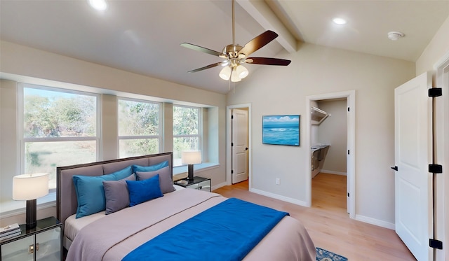 bedroom with ceiling fan, light hardwood / wood-style floors, a spacious closet, and vaulted ceiling with beams